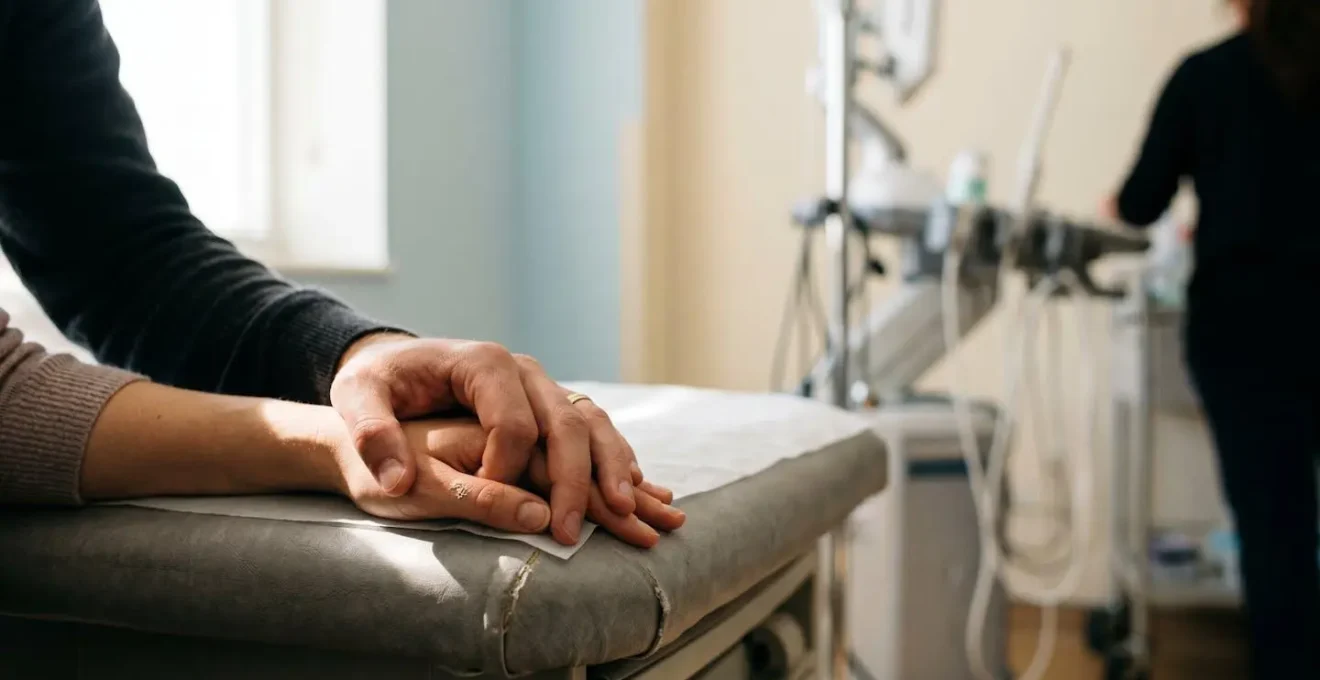 Couple tenant les mains l'un de l'autre pendant une échographie médicale encadrée, moment d'émotion partagée dans un cabinet médical français