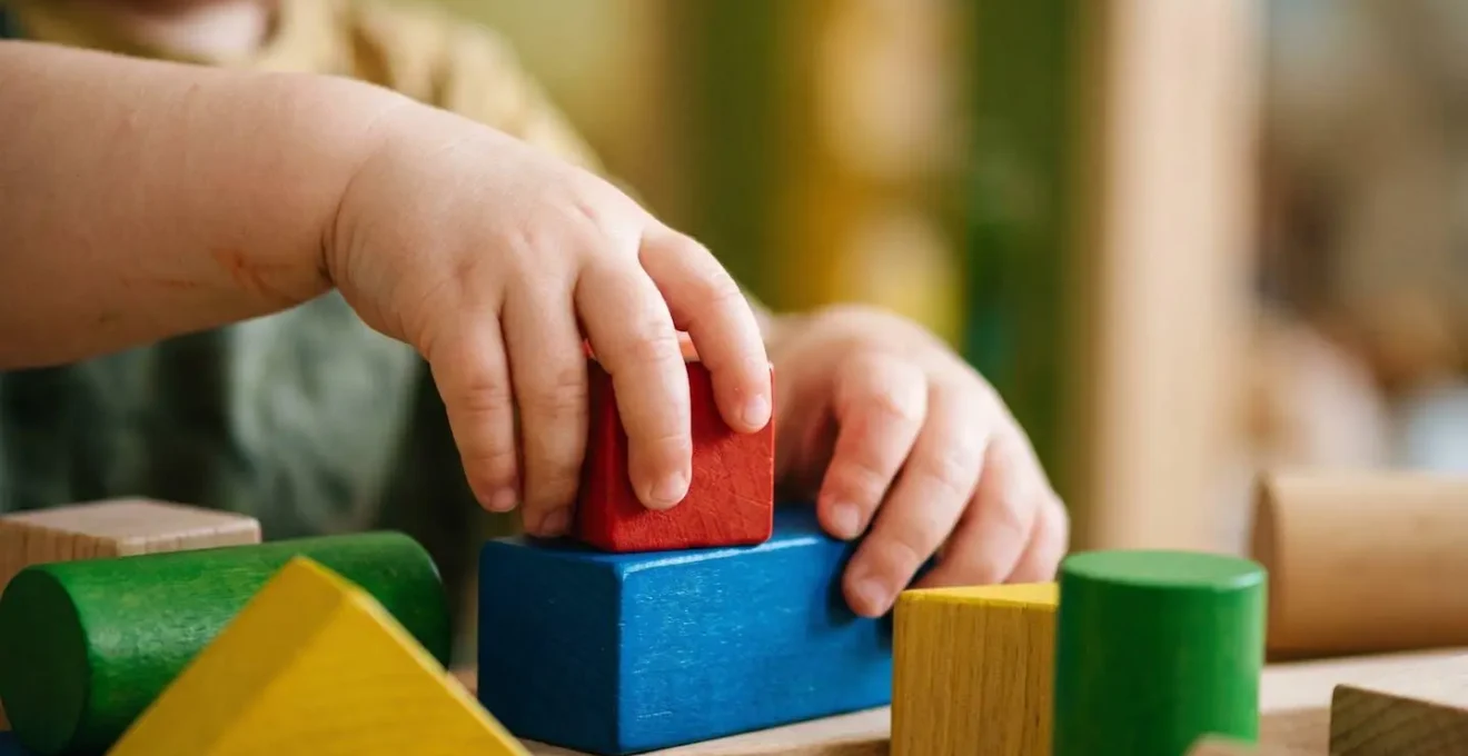 Gros plan macro sur les mains d'un jeune enfant manipulant un puzzle, symbolisant le développement cognitif en construction