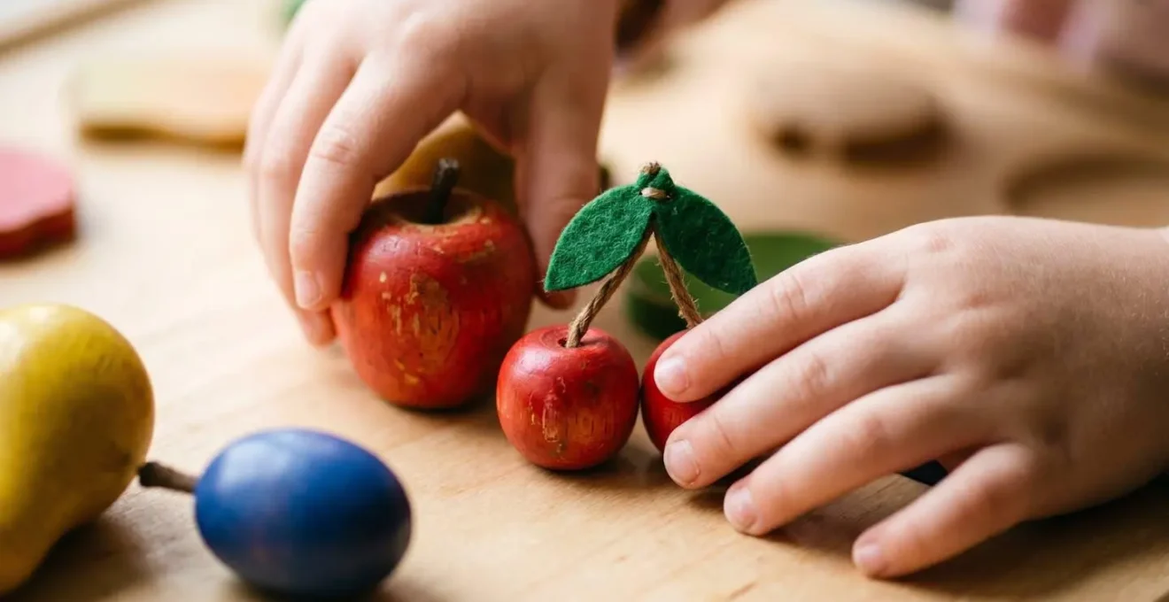 Mains d'enfants manipulant des fruits en bois colorés dans un jeu de société coopératif