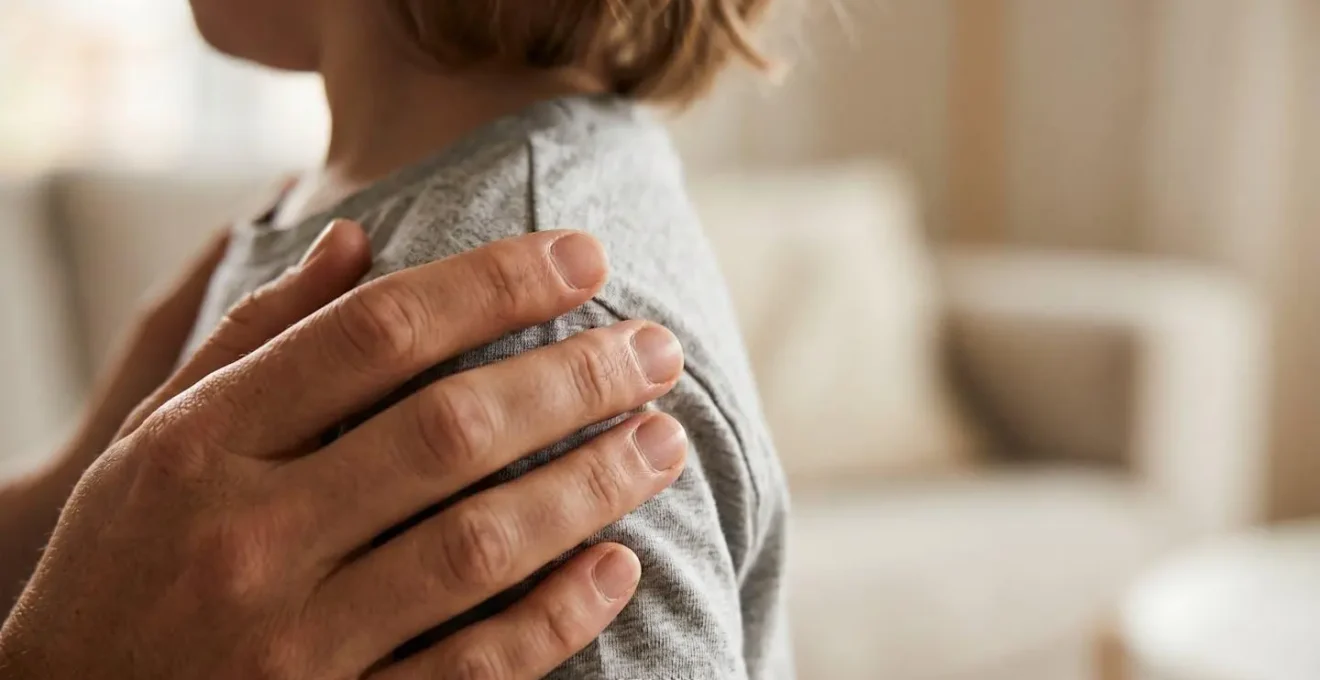 Gros plan sur les mains d'un parent posées doucement sur les épaules d'un enfant dans un moment d'écoute active